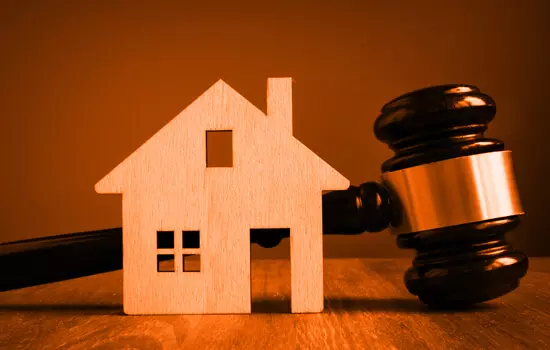 Bloc de bois représentant une maison devant un marteau de juge